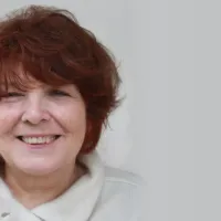 Portrait of the sculptor Jana Pfeifer with short reddish-brown hair, smiling against a light background